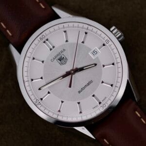 A Tag Heuer Carrera Caliber 5 Automatic WV211A.FC6203 with a silver case, brown leather strap, and the date displayed as the 15th.