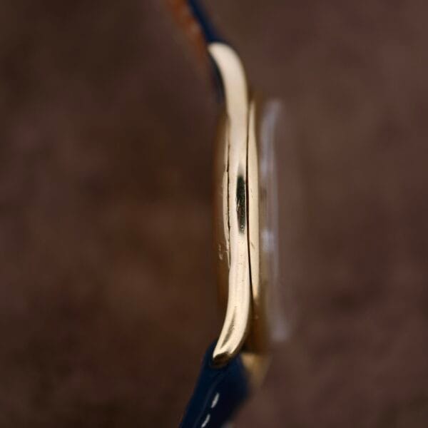 Close-up side view of the Vacheron Constantin 18k Gold Caltrava Cal. V453 with a blue strap, showcasing its thin profile against a soft brown background, emphasizing its timeless elegance.