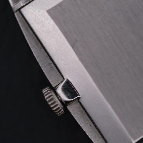 Close-up of the Vacheron Constantin 6761 Cal 1003s silver crown, located on the right side of a brushed metal case against a dark background, with its textured edge prominently visible.