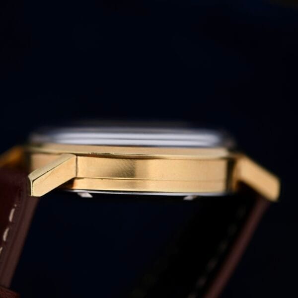 Close-up of an Omega Seamaster Chronograph Ref. 105.005 321 Caliber watch with a brown leather strap against a dark background, focusing on the side profile to highlight its polished metal and sleek design.