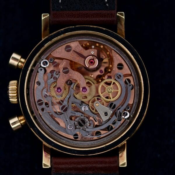 The Omega Seamaster Chronograph Ref. 105.005 321 Caliber showcases interlocking gears and intricate mechanisms in a gold-tone casing with an open back and brown leather strap, epitomizing elegance and precision in every detail.