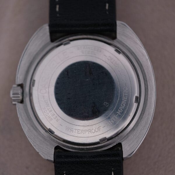 Back view of a Caravelle Automatic Ref 745 Diver “Jet Seconds” Super Waterproof watch with stainless steel body and black leather strap. Engraved text highlights shock resistance and waterproof features. Subtle signs of wear tell stories of time well spent.