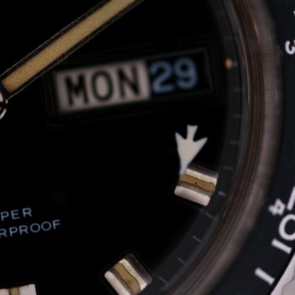 Close-up of a Caravelle Automatic Ref 745 Diver “Jet Seconds” Super Waterproof watch face showing the day MON and date 29. The black face has luminous hands and markers, with partially visible text.