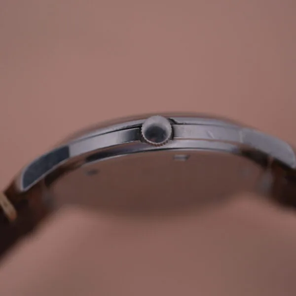 Side view of a Girard Perregaux Sea Hawk watch reveals a polished metal case and a crown for time adjustment, elegantly paired with a brown leather strap.