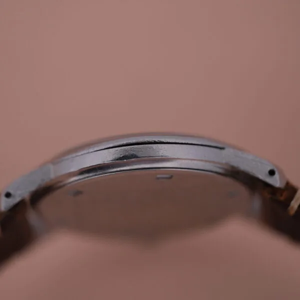 The Girard Perregaux Sea Hawk watch, with its sleek silver case and brown leather strap, is shown from the side against a neutral background to accentuate its slim profile.