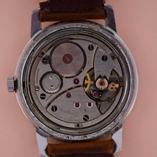 A close-up of the Girard Perregaux Sea Hawk reveals its intricate gears and mechanisms, all encased in metal with a brown leather strap, showcasing exceptional precision engineering and craftsmanship.