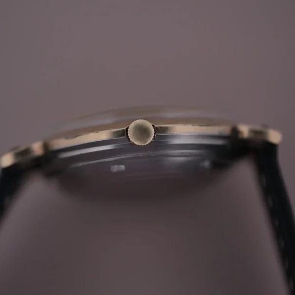 Close-up of the Hamilton Kinematic Swiss Automatic Fancy Lugs wristwatch, showcasing its sleek side profile, highlighting the crown and thin case design. The elegant metallic casing contrasts beautifully with the dark strap against a blurred background.