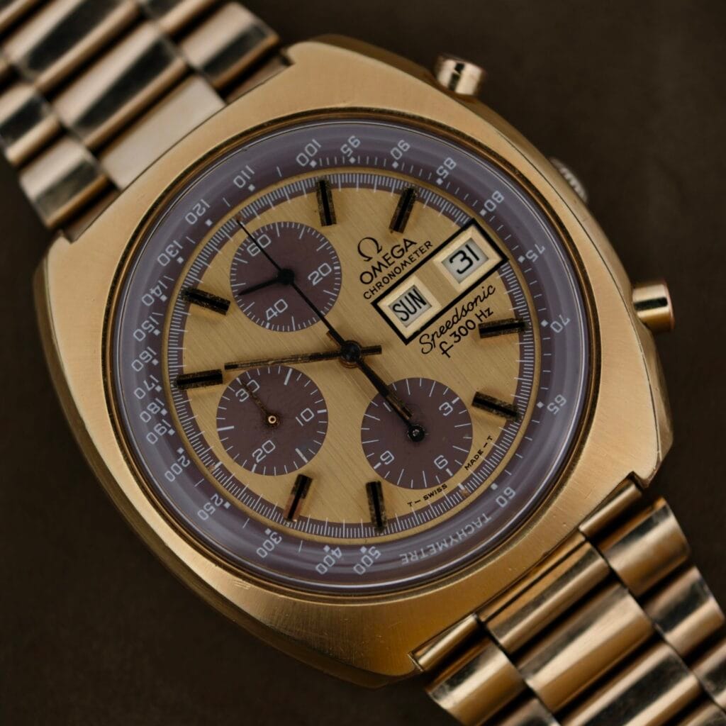 Close-up of a gold 1975 Omega Speedsonic f 300Hz Chronograph Ref. 188.0002 featuring a tachymeter bezel and day-date display.