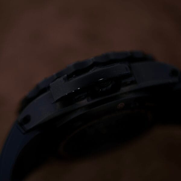 Close-up of a Luminox Scott Cassell Deep Dive Special 1526 Automatic wristwatch, highlighting the watch case and band. The image showcases the texture and detail of the dark material against a blurred brown backdrop.