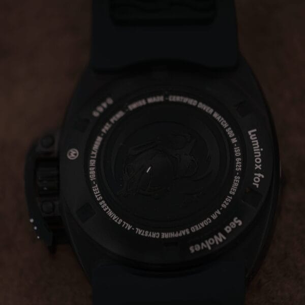 The rear of the Luminox Scott Cassell Deep Dive Special 1526 Automatic watch showcases intricate engravings, displaying model and brand details with a textured circular pattern. It features a dark strap.