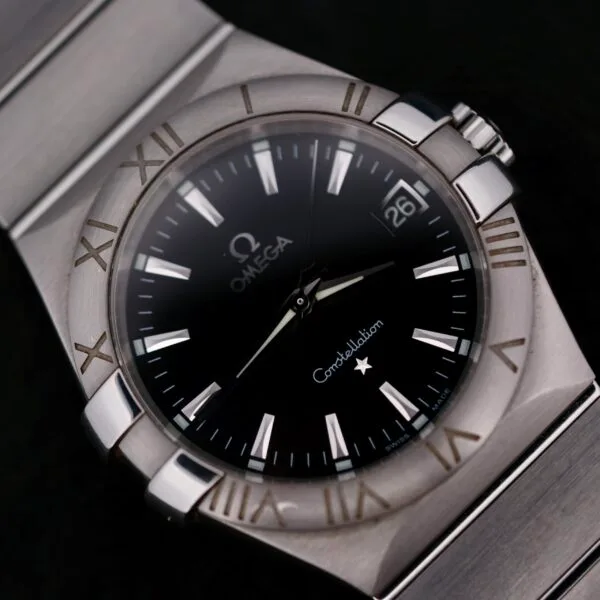 The Omega Constellation Ref. 396.201 features a black dial with the Omega logo and Constellation branding, silver Roman numerals, and a 3 oclock date window, complemented by its stainless steel bracelet.