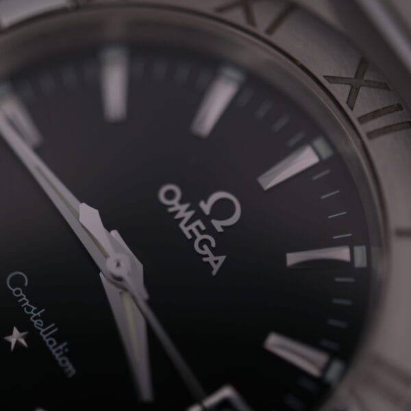 A close-up of the Omega Constellation Ref. 396.201 luxury watch reveals the Omega logo, a black dial with silver Roman numeral hour markers, Constellation above a star emblem, and silver-toned hands, all highlighting its elegance.