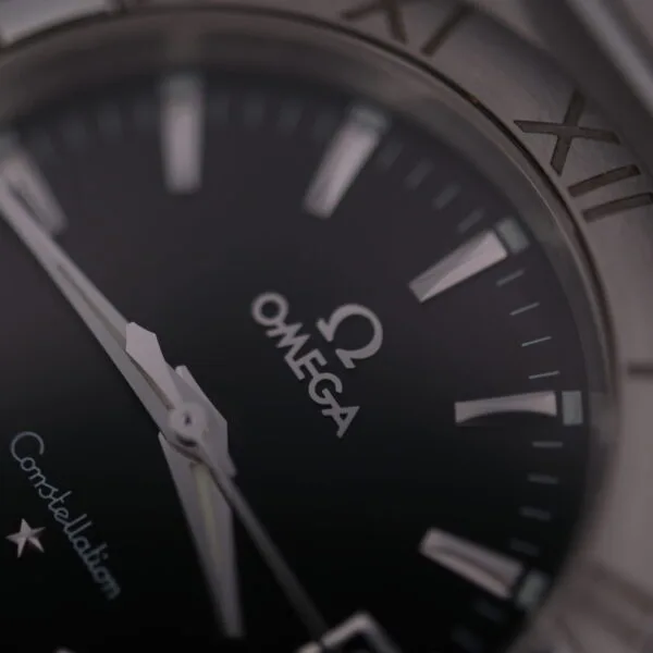 A close-up of the Omega Constellation Ref. 396.201 luxury watch reveals the Omega logo, a black dial with silver Roman numeral hour markers, Constellation above a star emblem, and silver-toned hands, all highlighting its elegance.