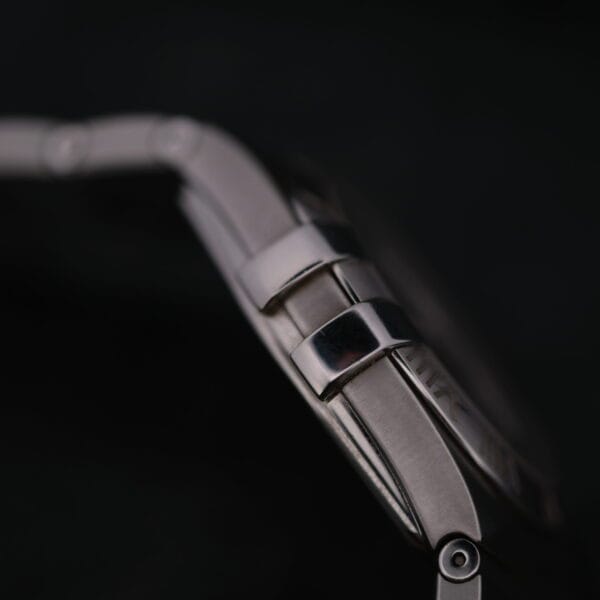 A close-up side view of the Omega Constellation Ref. 396.201 wristwatch showcases the clasp and band links against a black background, with the rest of the watch in soft focus.