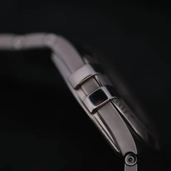 A close-up side view of the Omega Constellation Ref. 396.201 wristwatch showcases the clasp and band links against a black background, with the rest of the watch in soft focus.