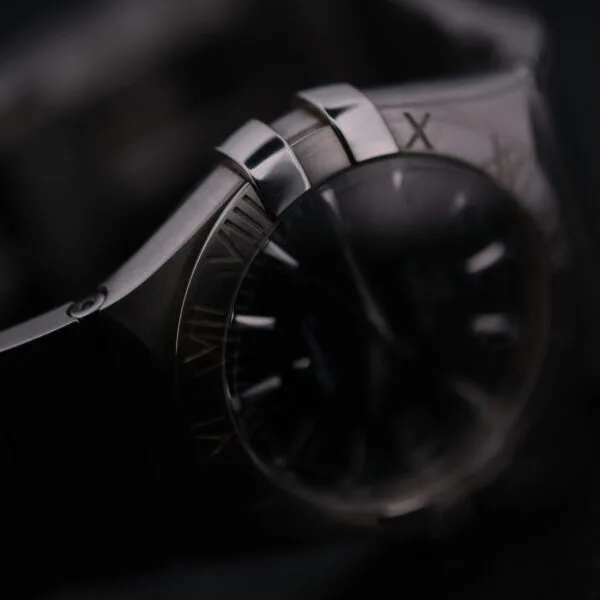 Close-up of the Omega Constellation Ref. 396.201, a luxury wristwatch with a polished metal bracelet and bezel, showcasing a partially visible face with Roman numerals and sleek design against a dark background.