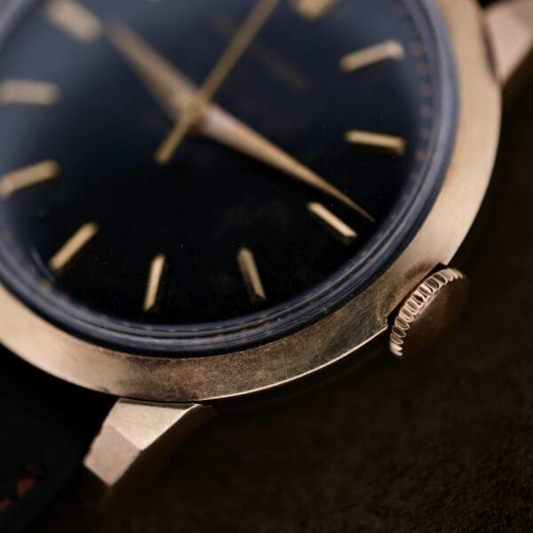 Close-up of the vintage Movado Ref. 18240 Francois Borgel Gold Top Hong Kong Market watch, showcasing a black dial with gold hour markers and hands. The crown is visible on the right, and the case has a patina, adding an aged classic look.