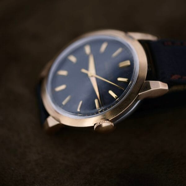 Close-up of a Movado Ref. 18240 Francois Borgel Gold Top wristwatch from the Hong Kong Market, featuring a gold-tone case, dark face with gold hour markers and hands, and a black leather strap set against an elegant dark background.