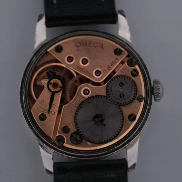 A close-up of the Omega Manual Wind Cal. 268s back showcases its intricate mechanical gears and components, elegantly set against a dark background.