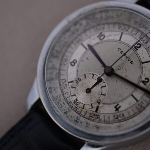 Close-up of the vintage Cevrus Monopusher Chronograph Sector Dial watch with a round, weathered dial, numbered markings, two black hands, a sub-dial, and a sleek black leather strap.