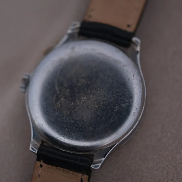 Close-up of the Cevrus Monopusher Chronograph Sector Dials weathered back, showcasing its scratched metallic cover and natural-colored leather strap.