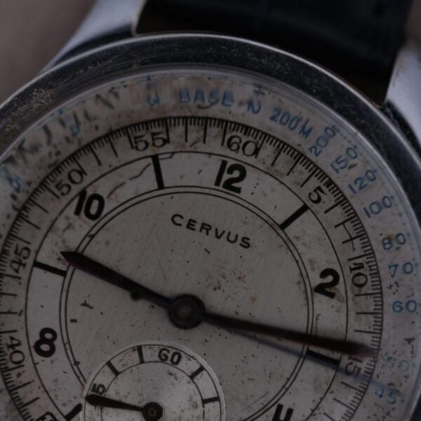 Close-up of a Cevrus Monopusher Chronograph Sector Dial wristwatch, featuring three hands and a small secondary dial. Its face displays weathered-style numbers marked Cervus, with an outer ring showcasing blue text for units and measurements.