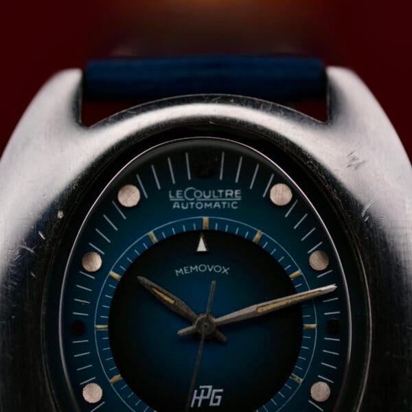 Close-up of a 1971 Jaeger LeCoultre Memovox Egg automatic watch face. The enchanting blue dial features silver and white markings with an inner alarm dial, complemented by silver-toned hands. The case exudes character with its signs of wear.