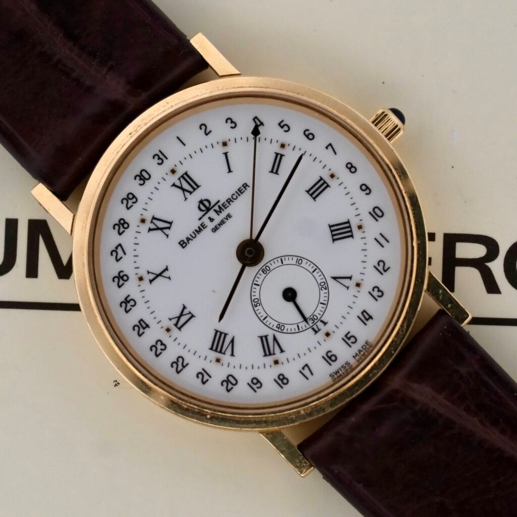 Baume Mercier 18k Gold Calendar Ref 15162 wristwatch featuring Roman numerals and a brown leather strap.