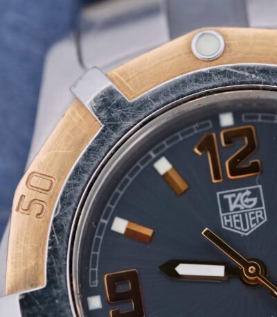 Tag Heuer 2000 - The Tag Heuer 2000 Exclusive WN1154 is a Swiss-made quartz watch from around September 2000. It features a 38mm case made of 18k yellow gold and stainless steel, complemented by a stainless steel strap. The gray dial includes central seconds, hack second, lume, and a rotating bezel. The watch does not come with its original box or papers.