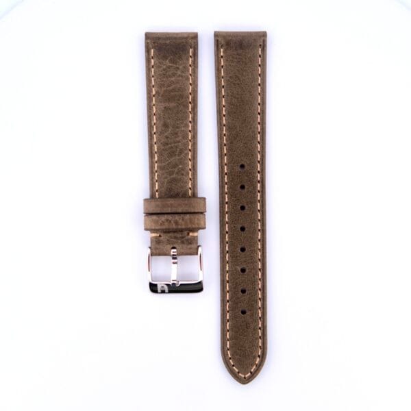 The Simple Stitch Vintage Leather Watch Strap in matte brown leather features beige stitching, a silver buckle, and multiple adjustment holes. Its displayed vertically against a white backdrop, adding a timeless touch to any classic timepiece.
