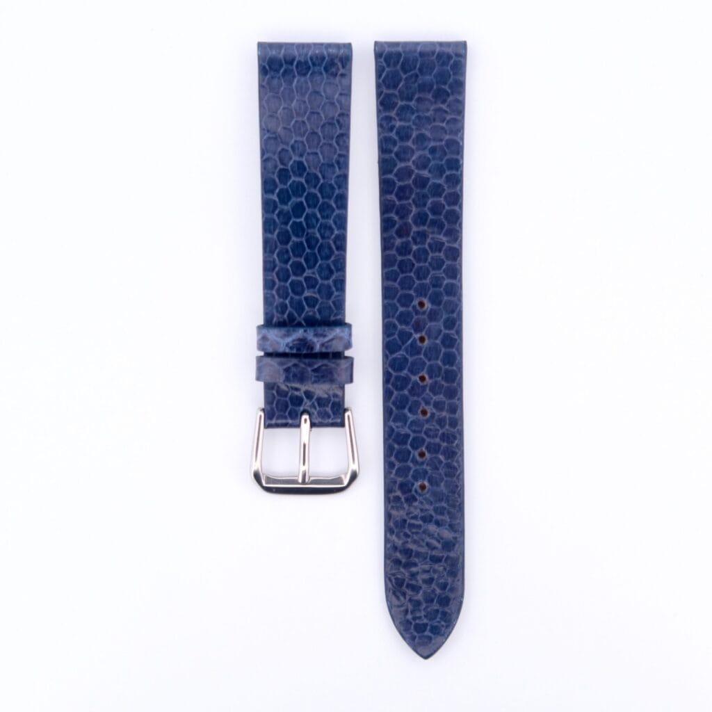 The Blue Snake Skin Handmade Leather Watch Strap has a hexagonal texture and lies flat on a white background. It features two parts: one with a silver buckle and another with multiple adjustment holes, seamlessly blending timeless elegance with modern design.