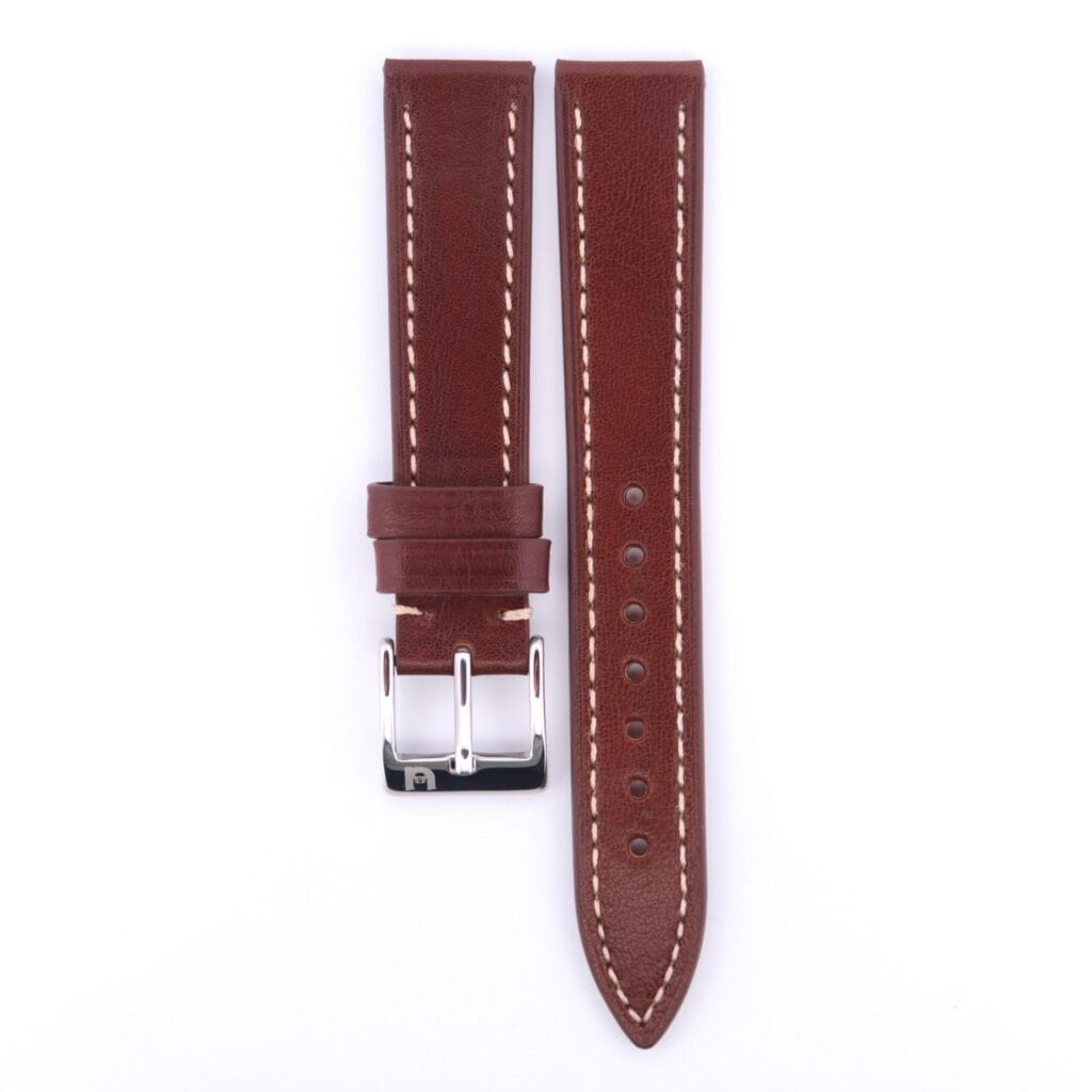 The Simple Stitch Classic Leather Watch Strap, made of brown leather with white stitching and a silver buckle, evokes a vintage feel. Its displayed against a plain white background.