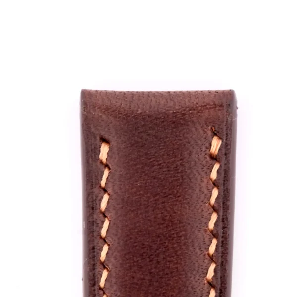 Close-up of a Dark Brown Genuine Horween Shell Cordovan watch strap showing its texture and the neat, golden stitches against a plain white background.