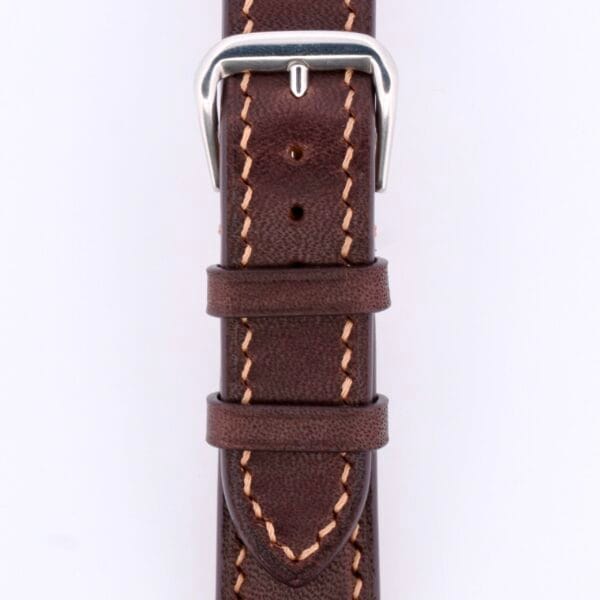 Close-up of a Dark Brown Genuine Horween Shell Cordovan Watch Strap with beige stitching and a silver buckle, neatly looped and secured. The renowned texture and color contrast highlight the luxury of Cordovan craftsmanship.