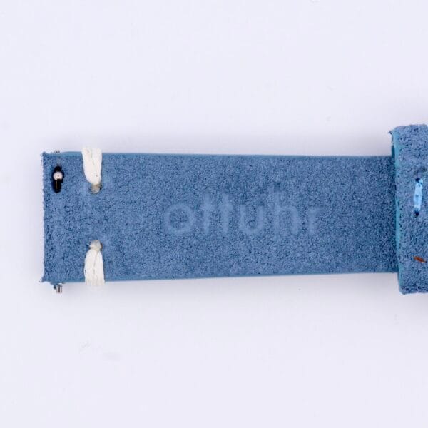 Close-up of the Powder Blue Suede Watch Strap Vintage Stitch, featuring visible fabric texture and metal pins. Subtle embossed text enhances its timeless charm.