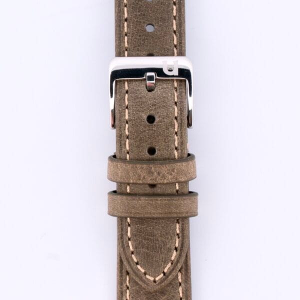 The Simple Stitch Vintage Leather Watch Strap, featuring a matte brown leather with white stitching and a shiny silver buckle clasp, offers vintage elegance. Its designed with multiple size adjustment holes and loops for security, all accentuated by the plain white background to highlight its timeless appeal.