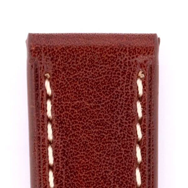 A close-up of the Simple Stitch Classic Leather Watch Strap shows its rich brown leather with white edge stitching against a white background. The texture, slightly rough, enhances its timeless appeal.