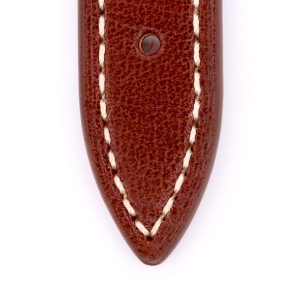 The Simple Stitch Classic Leather Watch Strap features a brown leather design with white edge stitching reminiscent of a vintage watch band. A round metal rivet is visible near the top center, and the strap has a pointed end.