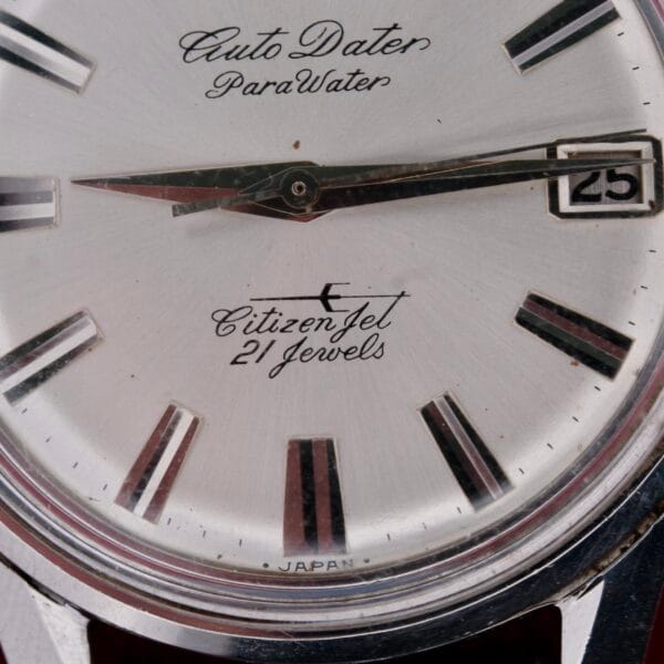 Close-up of a Citizen Jet Auto Dater Automatic Para Water watch face with 21 Jewels and date in a small window on the right, featuring metallic hour markers and hands. Made in Japan.