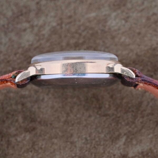Side view of the Girard Perregaux Military Dial Small Seconds wristwatch featuring a brown leather strap and metallic case. The watch face is concealed, emphasizing its sleek military-inspired profile against a neutral background.