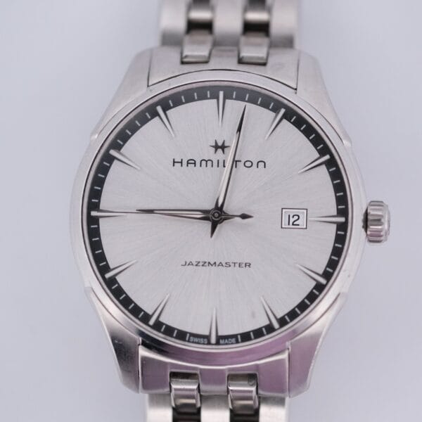 The Hamilton Jazz Master Stainless Steel watch features a sleek silver design with a stainless steel bracelet, a date display at 3 oclock, and a light silver dial accented by black hour markers and hands.