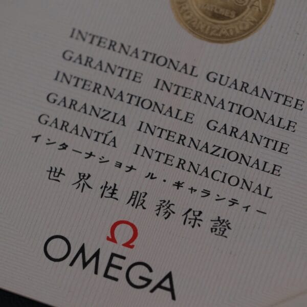 Close-up of an Omega Seamaster Deville Automatic international guarantee card for the Japanese market, featuring the word guarantee in various languages, including English, French, Italian, Spanish, Japanese, and Chinese, alongside the classic Omega logo and emblem.