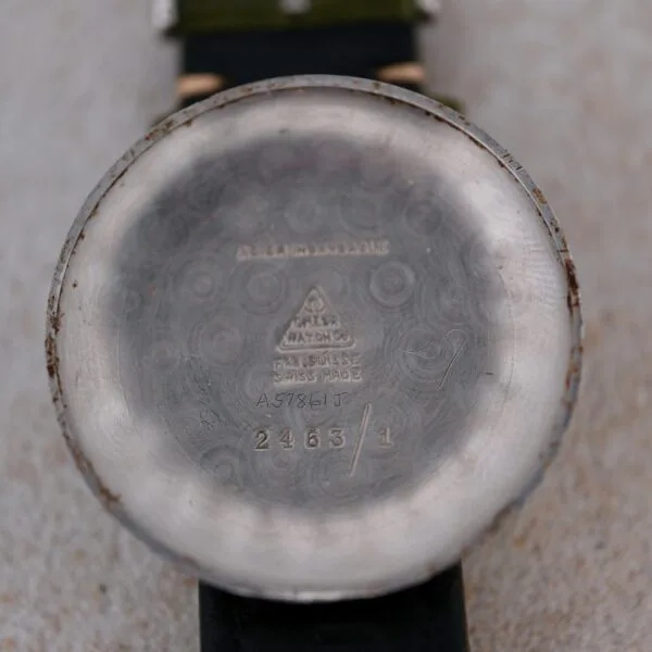 A close-up of the back of a silver Omega Turler Dial Chronograph Caliber 320 wristwatch case features etched text like ACIER INOXYDABLE, BREVET + 642249, and FAB. SUISSE SWISS MADE. The watch has a green strap.