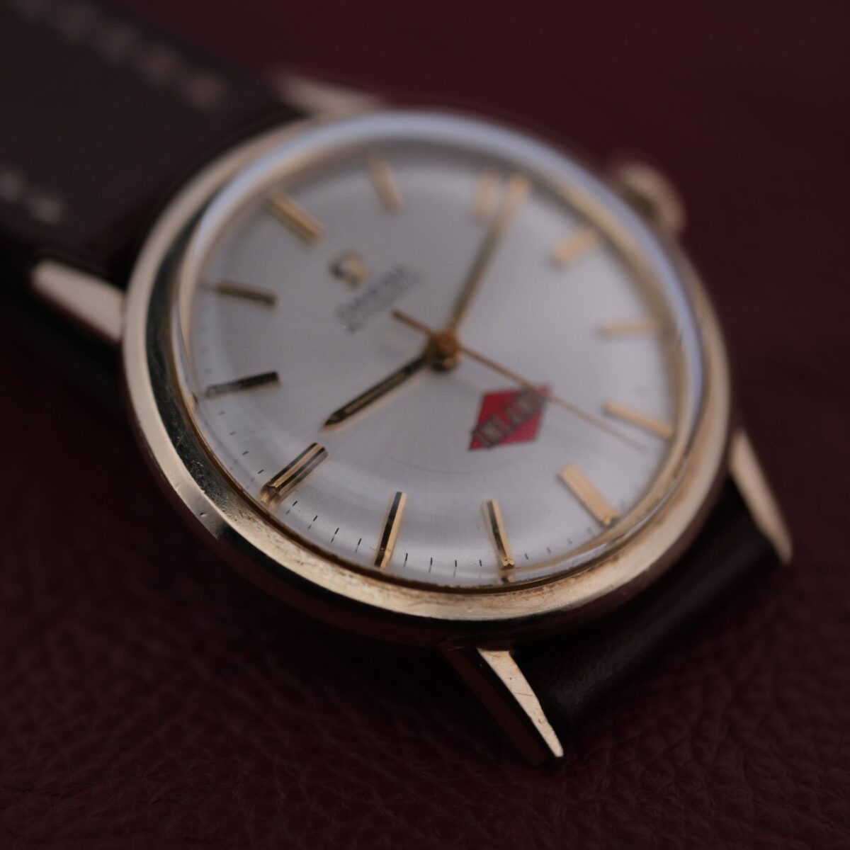 Introducing the Omega Automatic Cal. 551 for Inland Company, a Swiss-made timepiece from 1960-69, featuring a 34mm 14k gold-filled case and a white dial with gold hour markers and hands. Powered by the Caliber 551 automatic movement, it offers reliable timekeeping without manual winding. The watch includes an 18mm leather strap and lacks a central seconds hand, maintaining a clean design. With reference number LU6304, this elegant and durable watch is a collector's gem, epitomizing Omega's precision and style.