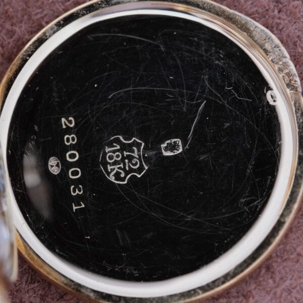 Close-up of the inside of a Cartier Officer Watch 18k Gold Roman Numerals Edmond Jager case, showing an 18K hallmark, crest, numbers 12 and 280031, and light surface scratches on the shiny circular metal case.