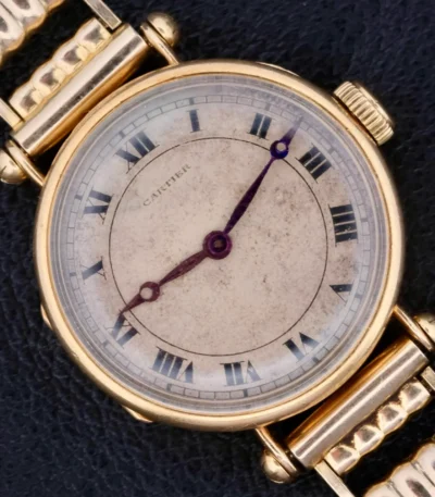 The 1910s Cartier Officer Watch in 18k gold, featuring Roman numerals and an Edmond Jager movement, epitomizes early 20th-century elegance and craftsmanship. This 28mm wide timepiece boasts a white dial with black Roman numerals and blued hands, encapsulating Cartier's refined aesthetic. The involvement of renowned watchmaker Edmond Jager ensures superior mechanical quality. Though it lacks original box and papers, it comes with a one-year warranty and an Ottuhr travel box and pouch. This watch is not just a luxury item but a significant collector's piece, blending Cartier's design excellence with Jager's technical prowess.