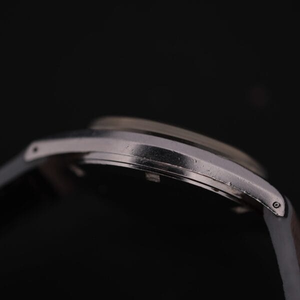 A close-up of the Certina DS 1st Gen Cal. 25-36 Stainless Steel wristwatch case against a black background, showing scratches and wear on the metal surface.