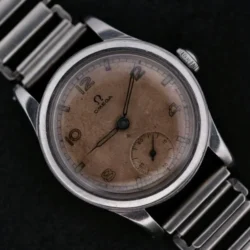 Displayed is the Omega WWII Era Military Sub Seconds wristwatch, featuring a metal link band and a weathered round dial. It has Arabic numerals at 3, 9, and 12 oclock with a small seconds subdial at 6 oclock on a striking black background.