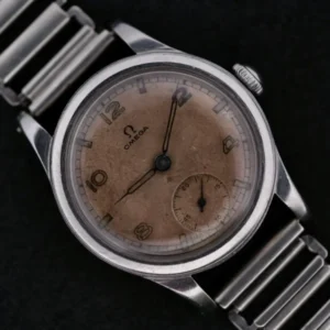 Displayed is the Omega WWII Era Military Sub Seconds wristwatch, featuring a metal link band and a weathered round dial. It has Arabic numerals at 3, 9, and 12 oclock with a small seconds subdial at 6 oclock on a striking black background.