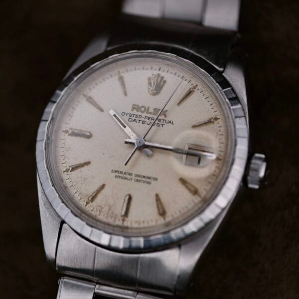 A close-up of the Rolex Oyster Perpetual Datejust 6605 Cal. 1066 exudes elegance with its silver metal band, slightly tarnished white dial, and silver hour markers and hands. The classic Rolex crown logo sits atop the face, epitomizing timeless luxury.